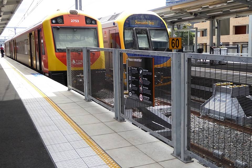 Deux trains sont arrêtés le long des voies ferrées entourées d'une clôture de sécurité 358.