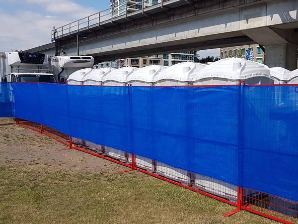 Un morceau de tissu d'ombrage bleu fonctionne avec la clôture temporaire du Canada pour empêcher le soufflage de la poussière.