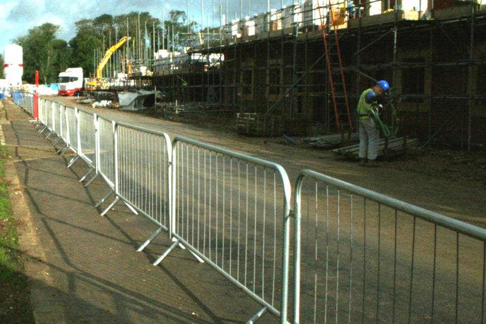 A worker is handling materials on the building construction site surrounded by crowd control barrier.