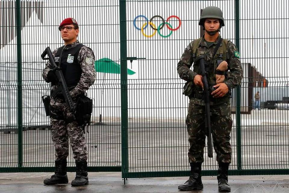 Deux soldats protègent la porte sinueuse de la clôture militaire soudée avec des fusils à la main.