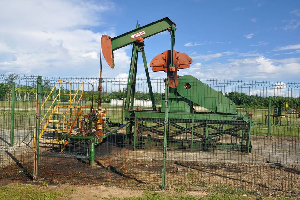 Une machine de développement du pétrole est garée dans la cour entourée d'une clôture soudée sinueuse.