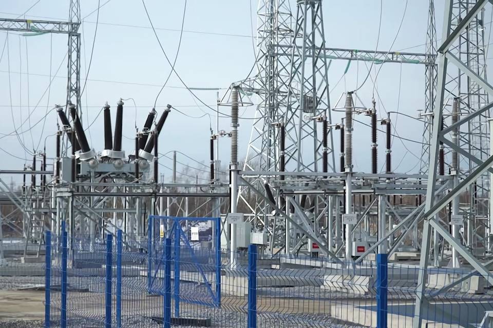 Un grand nombre d'installations électriques sont établies en plein air et entourées d'une clôture soudée sinueuse.