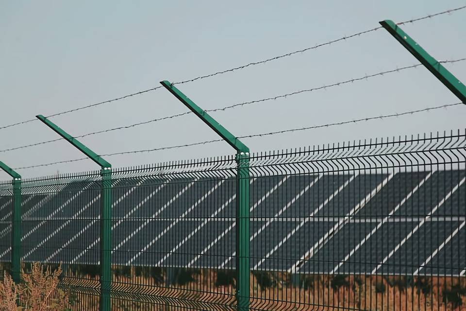 Los paneles solares están dispuestos en línea recta y están rodeados por una valla soldada con curvas.