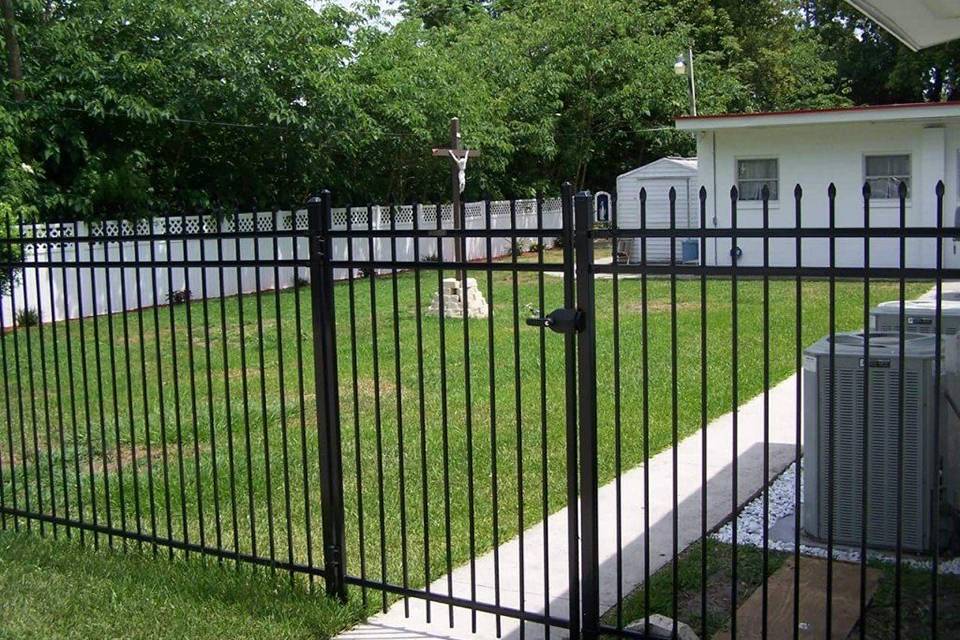 Une maison privée est entourée d'une clôture en acier avec une porte de clôture.